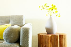 Modern grey sofa and side table with flower arrangement. Front view.